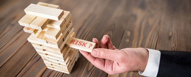 businessman pulling jenga piece reading risk