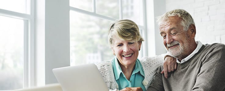 happy retired couple at computer