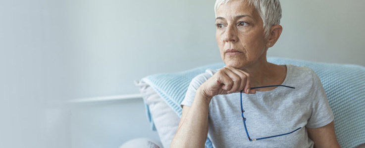 retired woman pondering and holding glasses