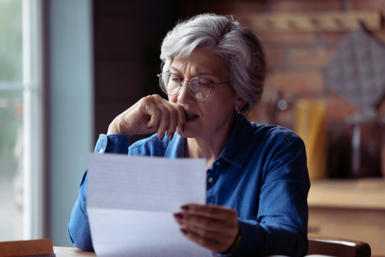 older woman looking at paper thoughtfully