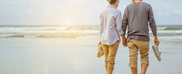 retired couple walking along beach